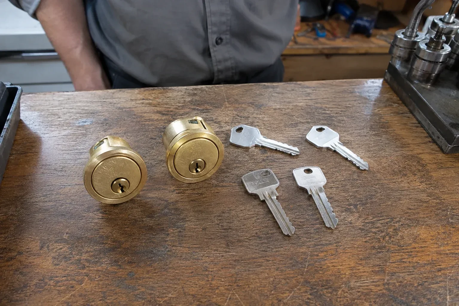 Two detached brass lock cylinders and four house keys on a wooden counter. — Lock Rekeying, Oakville